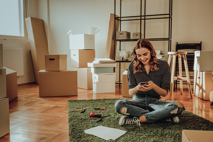 Young woman sitting on her floor getting ready to sell her house to cash buyers.